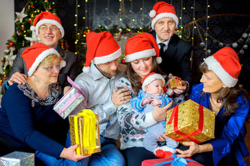 a big friendly family celebrates Christmas, gives gifts to the kid and has fun