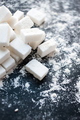 Unhealthy food concept - sugar  and flour on a black background. Dangerous high amount of sugar in food. Carbohydrates sources, top view.