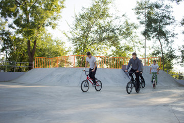 Obraz premium Group of young people with bmx bikes in skate plaza, stunt bicycle riders in skatepark 