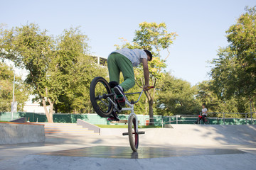BMX rider training and do tricks in street plaza, bicyxle stunt rider in cocncrete skatepark 