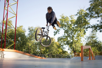 BMX rider training and do tricks in street plaza, bicyxle stunt rider in cocncrete skatepark