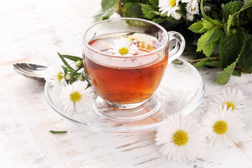 cup of tea with chamomile flowers on rustic background