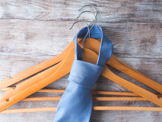 Wooden clothes hangers with man's elegant blue tie on wooden background. What nothing to wear...