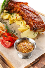 Delicious Grilled Pork Rib and Fried Potato with Sauce and vegetables on wooden cutting board