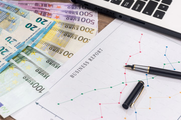 business graph with pen and laptop, euro banknote on desk