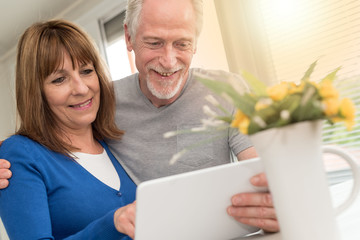Modern mature couple using tablet, light effect