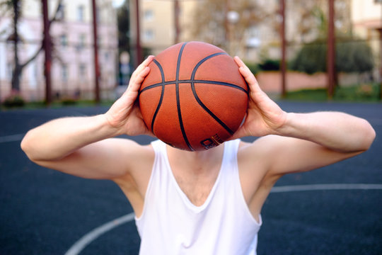 conceptual photo of basketball inspiration, man holding basketball ball instead of his head