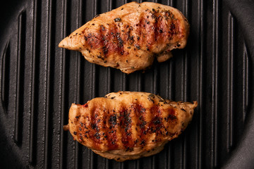 Grilled chicken breast fillets on black ribbed cooking pan