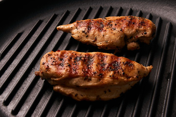 Grilled chicken breast fillets on black ribbed cooking pan