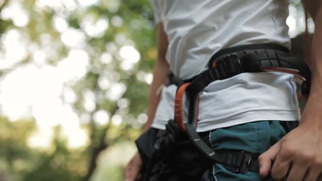 Rock climber wearing safety harness and climbing equipment, close up