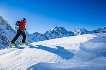 Photo sur Plexiglas Sports dhiver Ski de montagne marchant le long d& 39 une crête enneigée avec des skis dans le sac à dos. En arrière-plan bleu ciel nuageux et soleil brillant et Tre Cime, Drei Zinnen dans le Tyrol du Sud, Italie. Sport extrême d& 39 hiver d& 39 aventure.