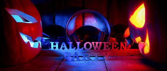 The concept of Halloween. Two glowing oranjous and blue light angry scary pumpkin with headphones and disks, a jack-off lantern, with an inscription Halloween party, on a wooden background