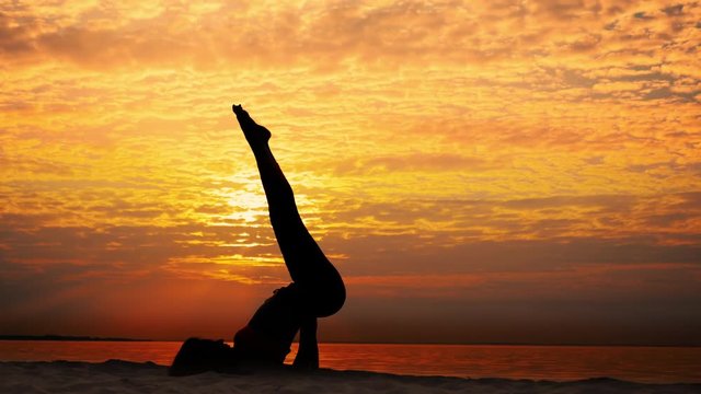 Female silhouette practicing yoga at sunrise