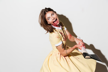 Side view of crazy screaming zombie woman attacking with axe