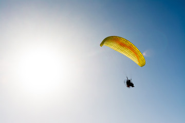 paraglider flying with paramotor on blue sky