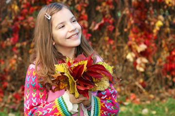 happy little girl holding autumn leaves