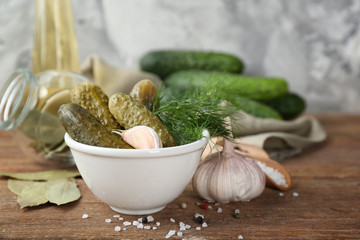 Bowl with pickled cucumbers on wooden table