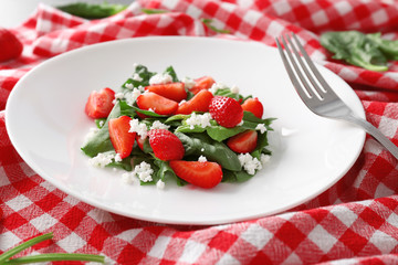 Plate with strawberry spinach salad on napkin