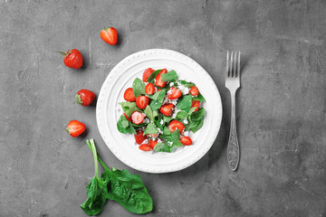 Plate with strawberry spinach salad on table