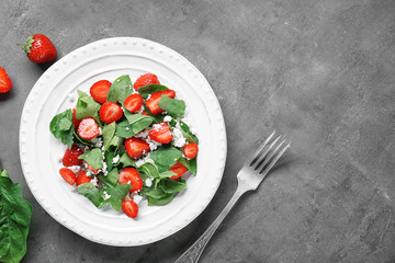 Plate with strawberry spinach salad on table