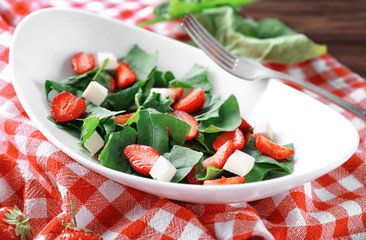 Plate with strawberry spinach salad on napkin