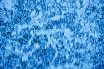 Out-of-focus bright blue flowing water as an abstract blurred water background