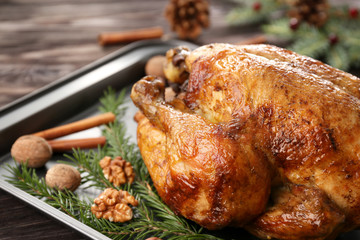 Roasted turkey with fir tree branches and nuts on baking sheet