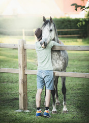 Young guy hugs his friend's horse