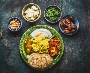 Various indian food bowls with curry, yogurt ,rice,bread ,chutney, paneer cheese and spices on dark rustic background, top view
