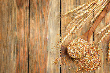 Composition with buckwheat and spoon on wooden background