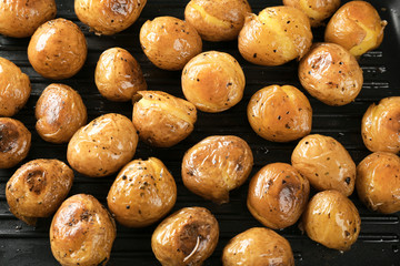Many baked potatoes on grill pan, closeup