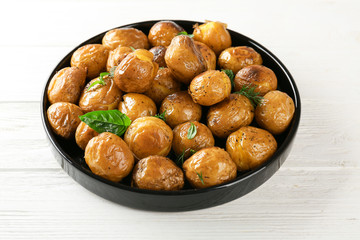 Black plate with baked potatoes on light background