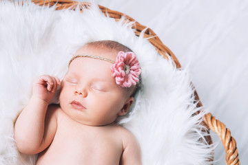 Sleeping newborn baby in a wrap on white blanket.