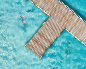 aerial view, wooden bridge laying to the sea with cleared water for swimming in island