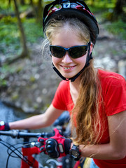 Fototapeta na wymiar Bicycle teen with ladies bikes in autumn park. Womens road bike for running on nature. Teenager girl in helmet cycling fording throught water. Sunglasses for travelers.