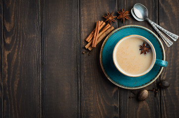 Indian masala chai tea. Spiced tea with milk on dark  wooden background.
