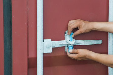 hand of worker attend to door locking handle with bolt sealing tie attached to the door locking handle retainer after completed inspected the cargo inside