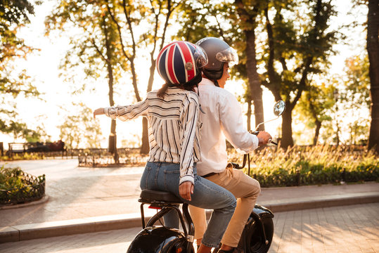 Back view of young african couple rides on modern motorbike