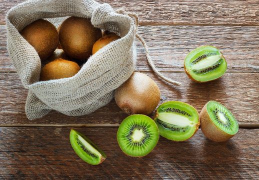 Fresh Kiwi fruit in bag on brown wooden background