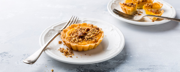 Thanksgiving day concept with homemad pumpkin tartlet, mini pie, on gray stone background. Healthy autumn food, copy space, banner.