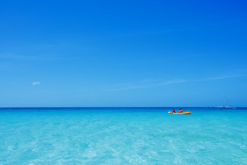 Two chirdren kayaking at tropical sea on yellow kayak