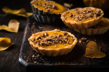 Thanksgiving day concept with homemad pumpkin tartlet, mini pie, on wooden background. Healthy...