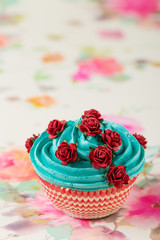 Blue cupcake decorated with fake red roses
