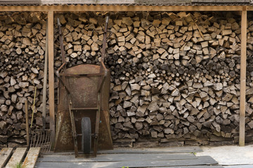 Schukarre und Werkzeug vor Holzstapel  - 173693259