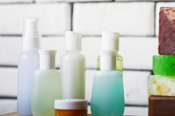 SPA procedures. Multicolored pieces of soap with candles, wax and bath salt. Bathroom accessories in a bright room with white brick.