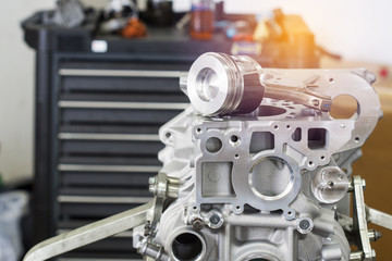 Selective focus Engine Block on a repair stand with Piston and Connecting Rod of Automotive technology with Blurred Tool cabinet background. Interior of a car repair shop.