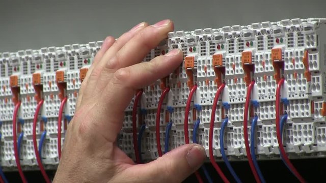 factory worker connecting electrical wires. Electrician testing electrical power
