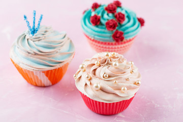 Three colorful cupcakes on pink background