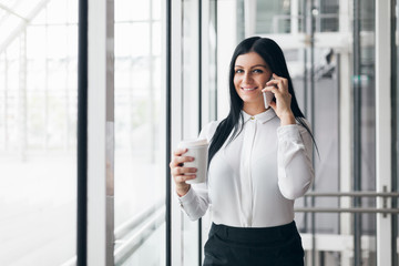 Successful business woman with coffee and smartphone in an office setting