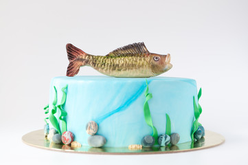 Art cake with fish, designed in the form of an underwater world with algae and pebbles. Picture for a menu or a confectionery catalog.